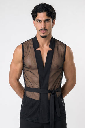 A man modeling a black sheer mesh wrap-style vest with a tie belt, photographed against a plain light gray studio background.